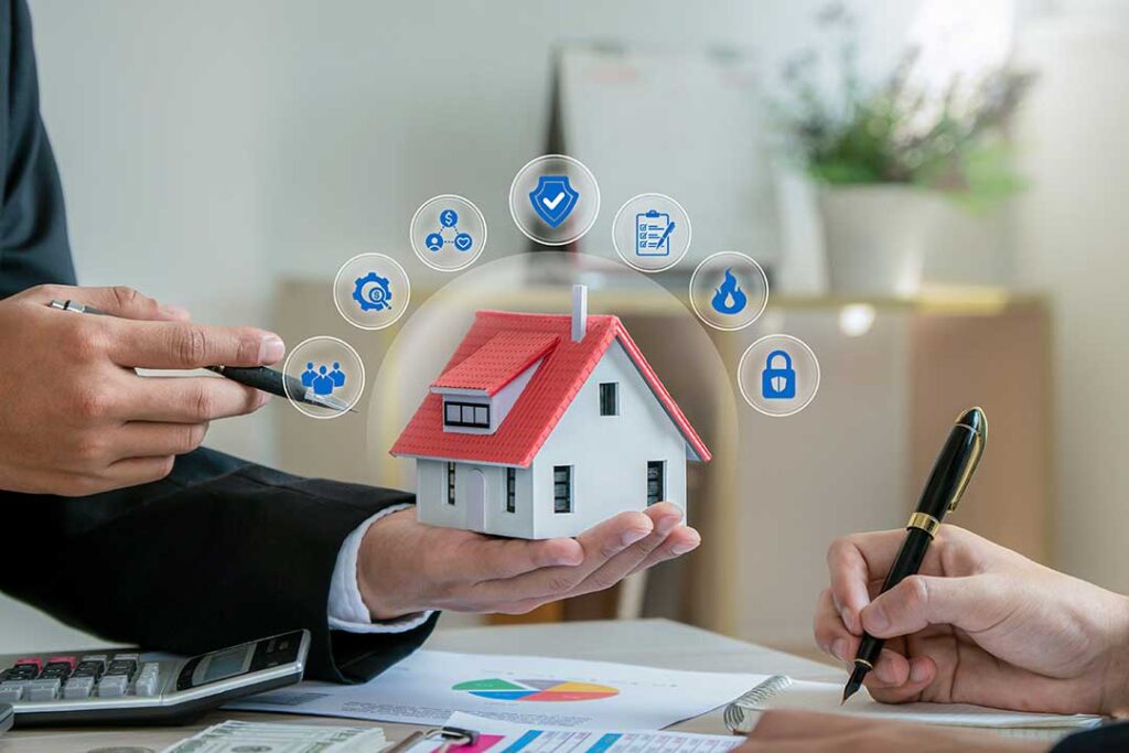 A couple reviews home and auto insurance documents beside a laptop and car keys.