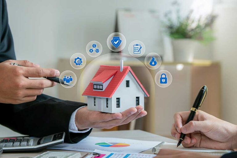 A couple reviews home and auto insurance documents beside a laptop and car keys.